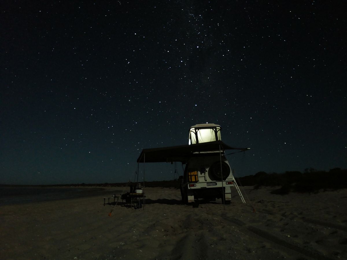 A vehicle under clear night sky with a rooftop tent