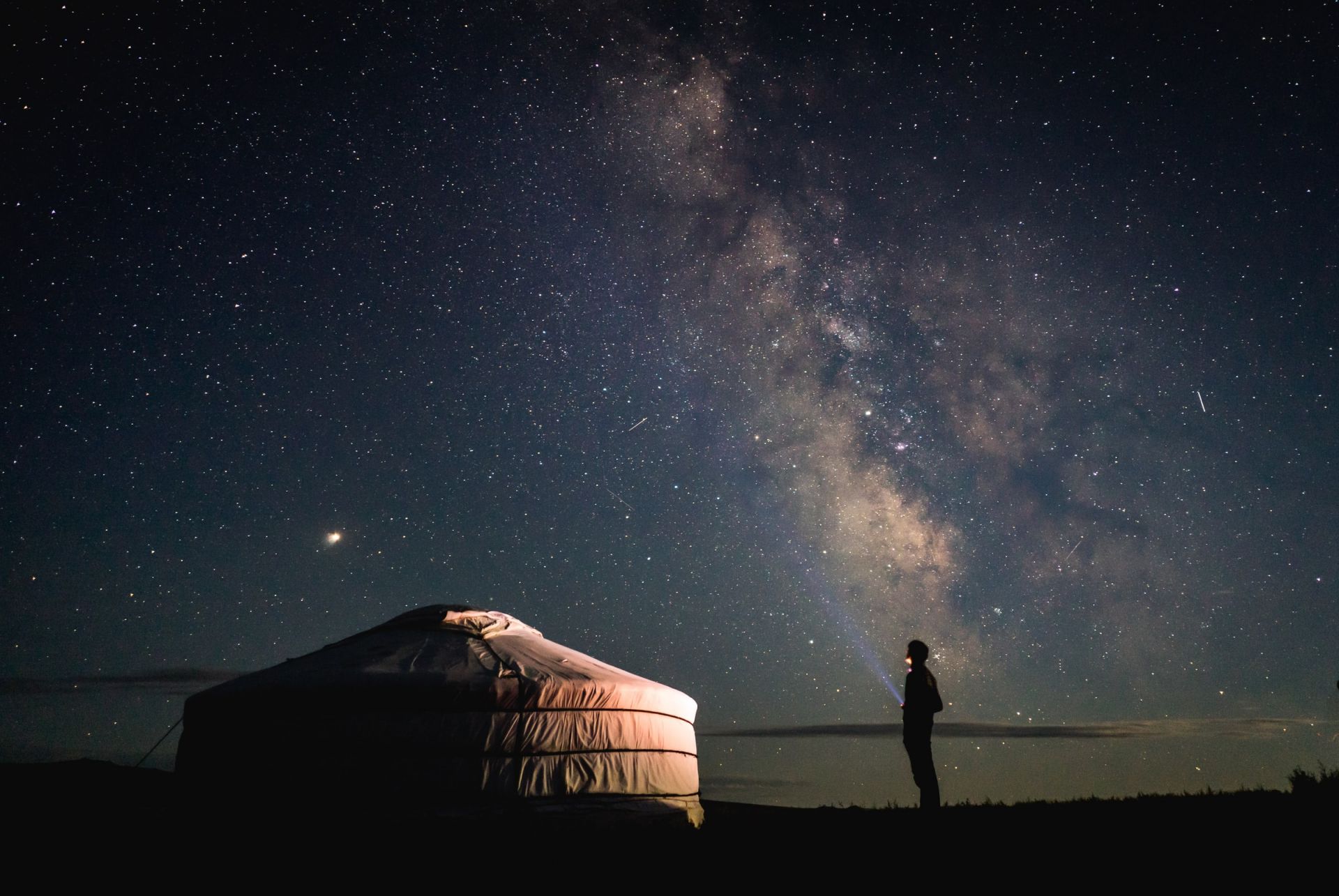 Man shining a torch at millions of stars in the sky