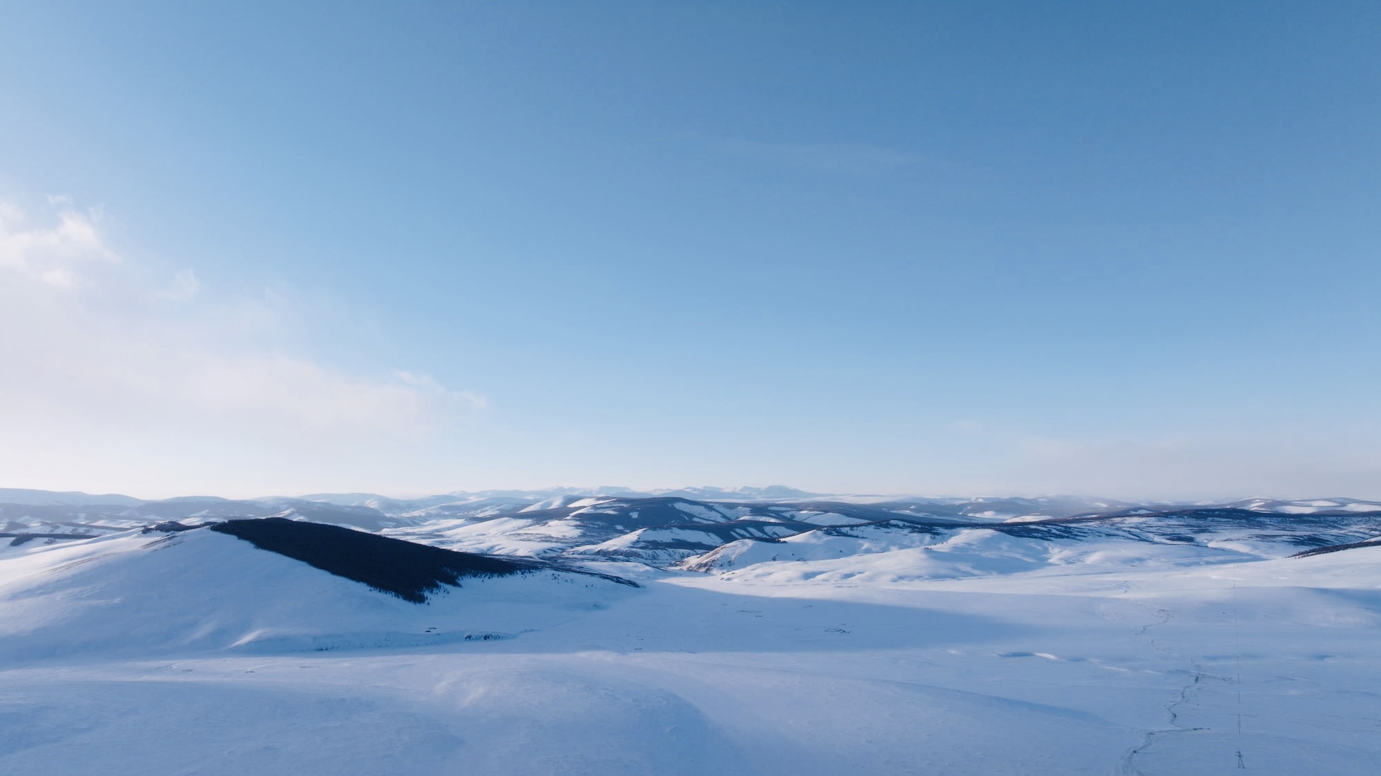 Mongolia’s rugged mountains, snow-covered under the eternal blue sky, perfect for a winter trip.