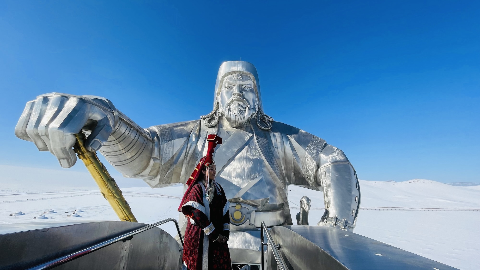 A person in traditional Mongolian attire poses by the popular tourist attractions.