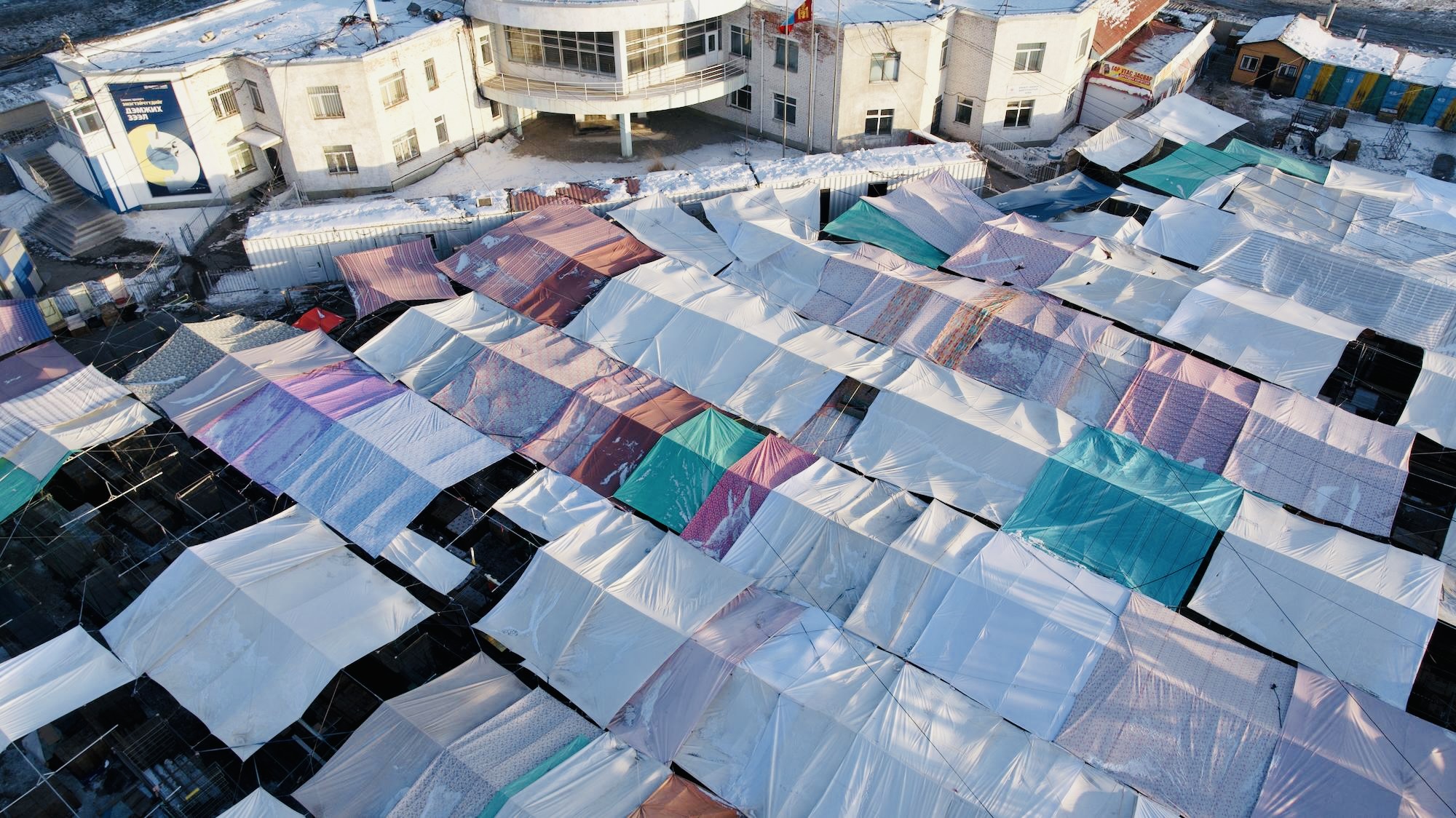 Tarp-covered stalls in a bustling winter market, a popular tourist attraction for seeking cozy wool socks.