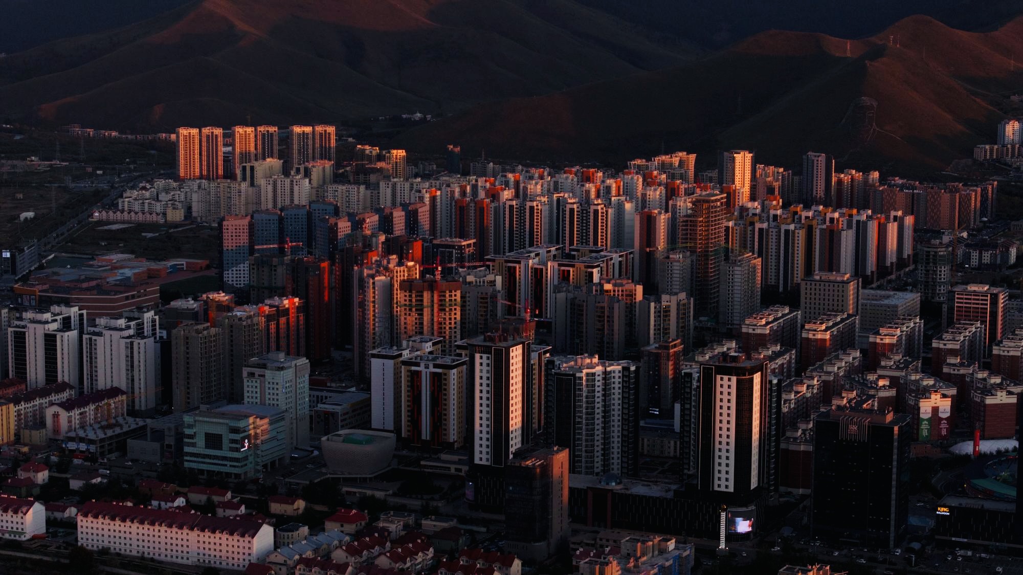 High-rise buildings glow warmly at dusk in the Mongolian winter.