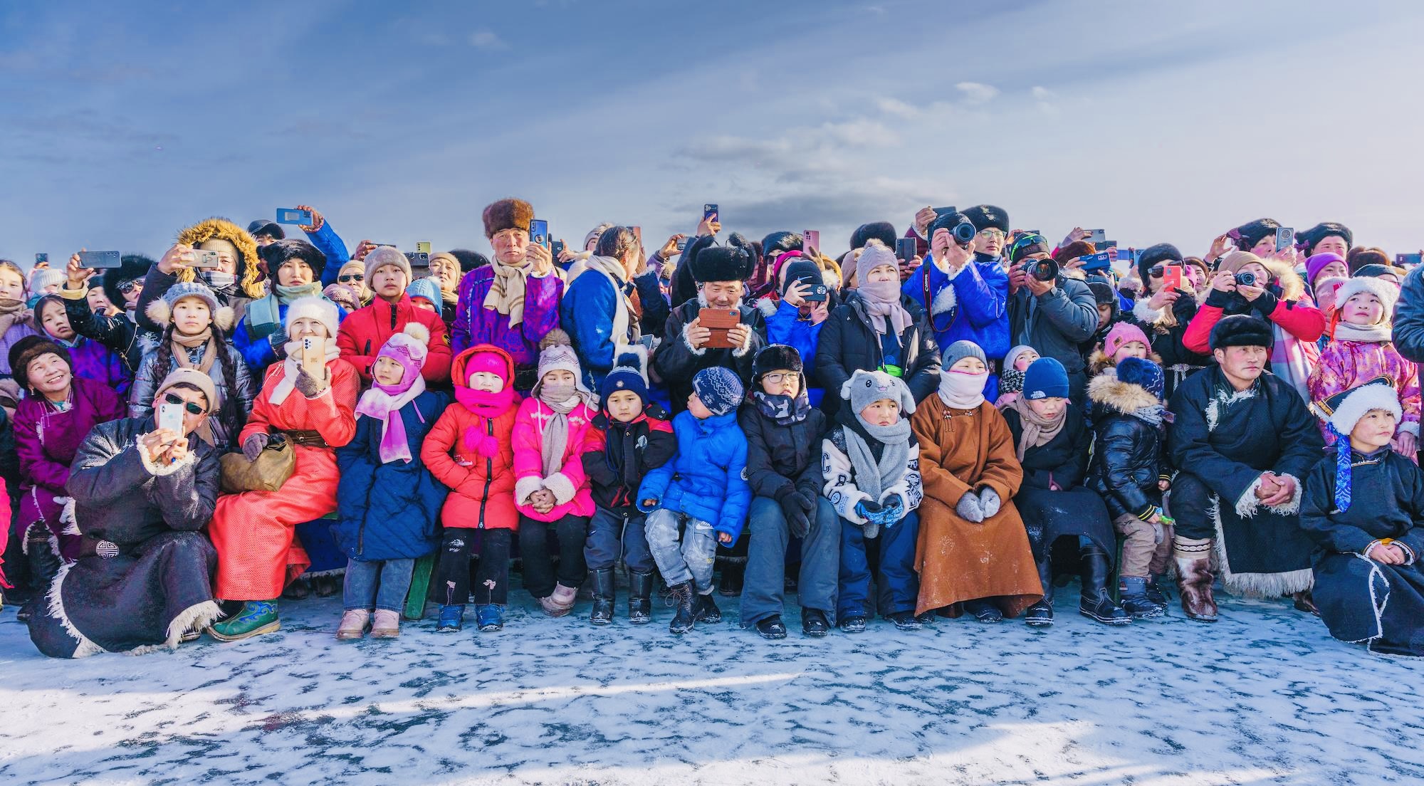 A crowd in traditional attire gathers, children bundled warmly, celebrating in the cold where wool socks are a must.