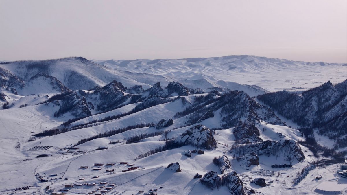 Mongolia’s rugged mountains, snow-covered under the eternal blue sky, perfect for a winter trip.