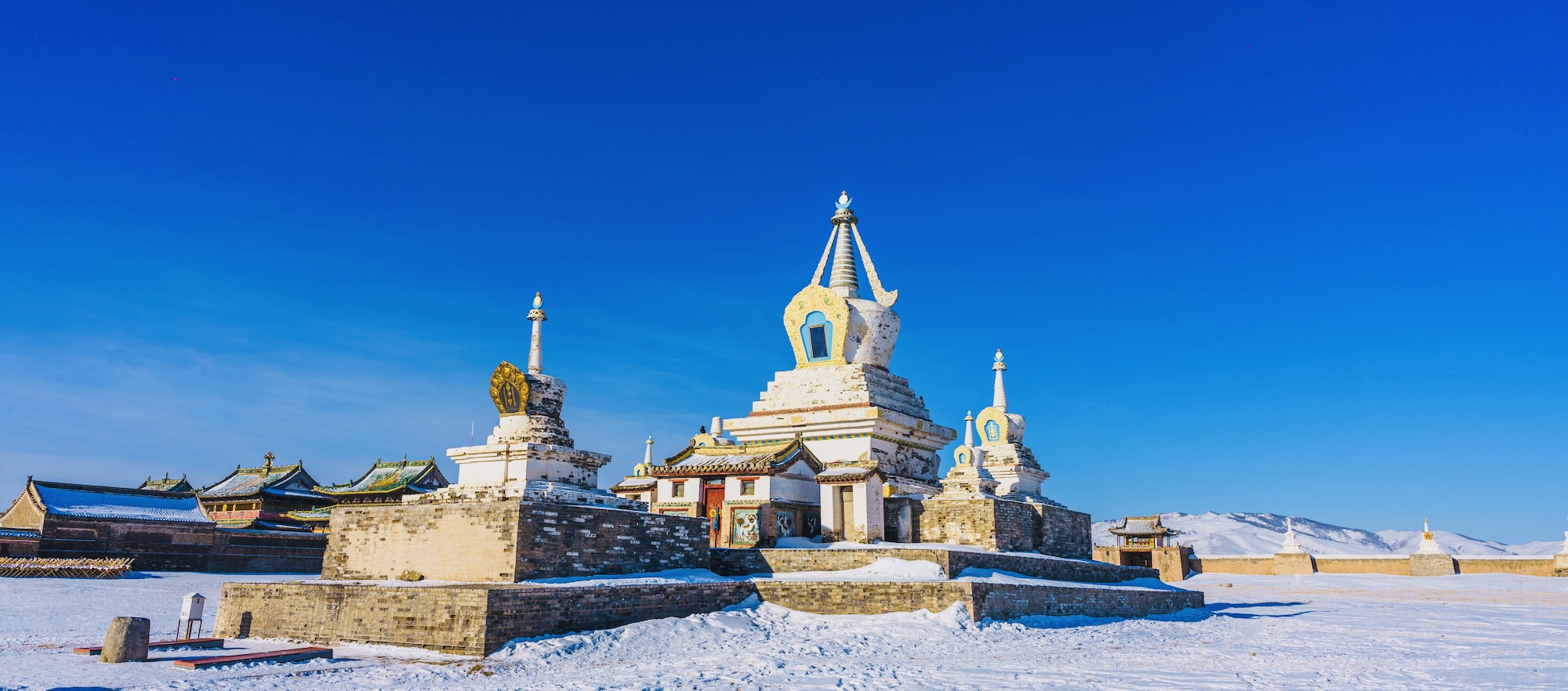 An ancient Mongolian temple stands serene in winter snow beneath the eternal blue sky.